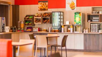 A modern cafe with a counter, seating area, and various food items displayed.
