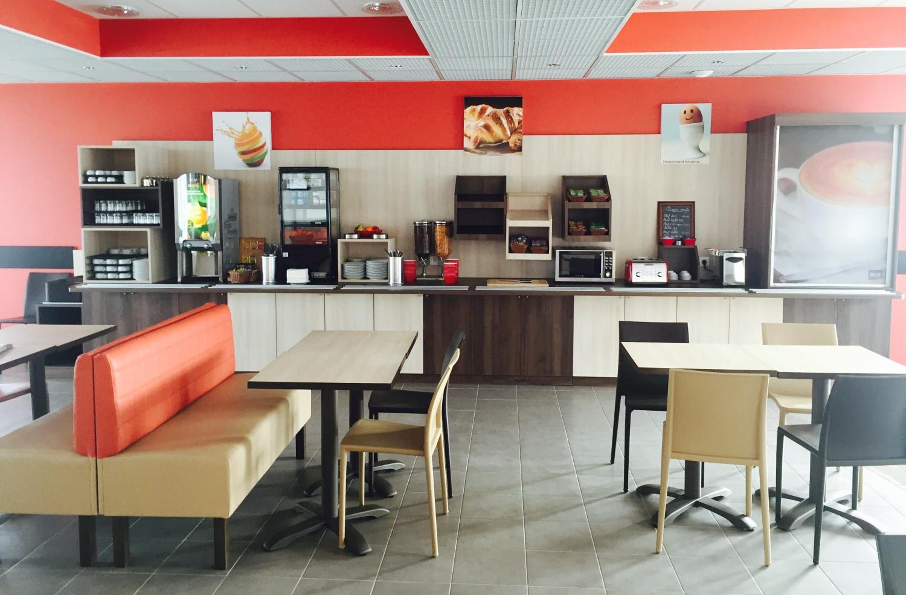 Interior de un restaurante de comida rápida con mesas, mostrador y diverso equipo para servicio de alimentos.