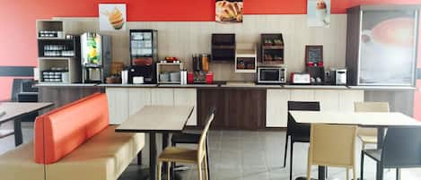 A fast-food restaurant interior with seating, a counter, and various food service equipment.