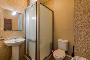 Une salle de bain équipée d’une douche, de toilettes, d’un lavabo et d’un miroir.