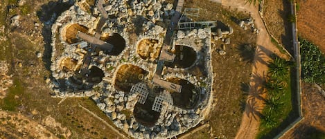 An aerial view of a historical site with ruins, pathways, and a wooden bridge.