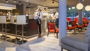 A modern bar area with a counter, stools, and seating. - Living Hotel Frankfurt (Frankfurt)