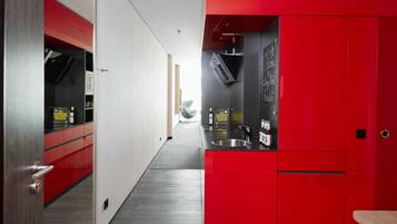 A modern kitchen with red cabinetry, a stainless steel sink, and a chalkboard with a welcome message.