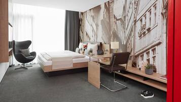 A modern hotel room with a bed, a desk, a chair, and a large window.