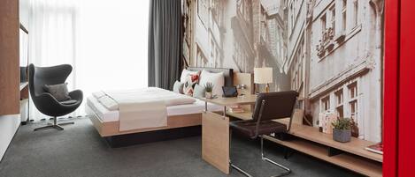 A modern hotel room with a bed, a desk, a chair, and a large window.