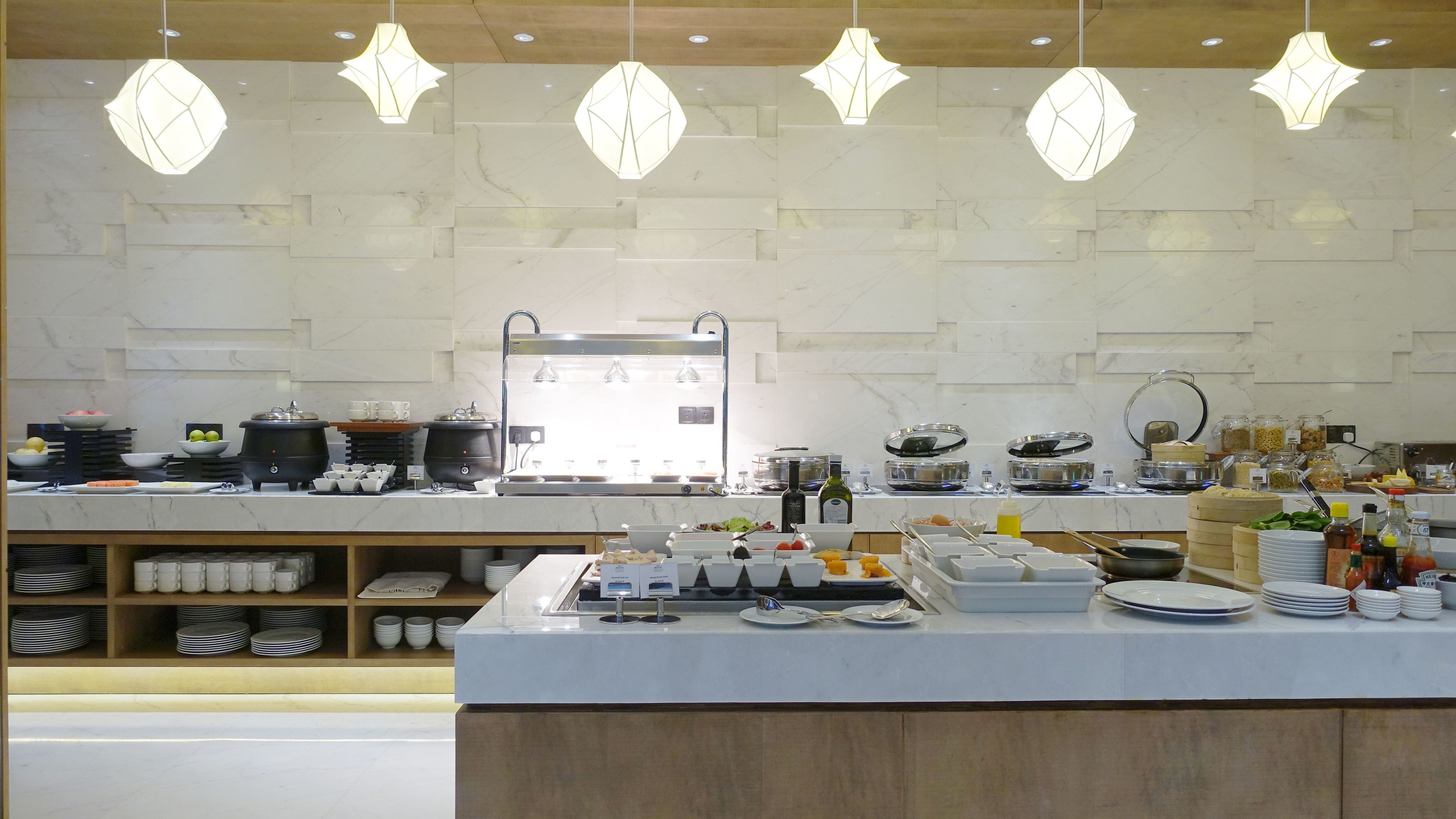 Un bufé de desayuno moderno con diversas opciones de comida, una estación de café y un diseño limpio y contemporáneo.