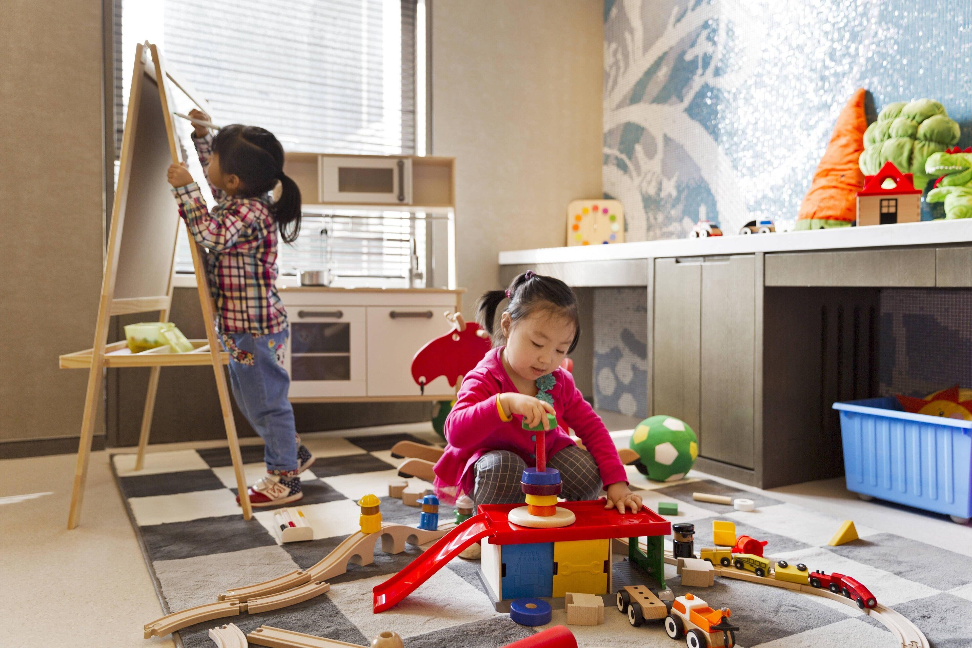 Un niño pintando sobre un lienzo en una habitación con zona de juegos.