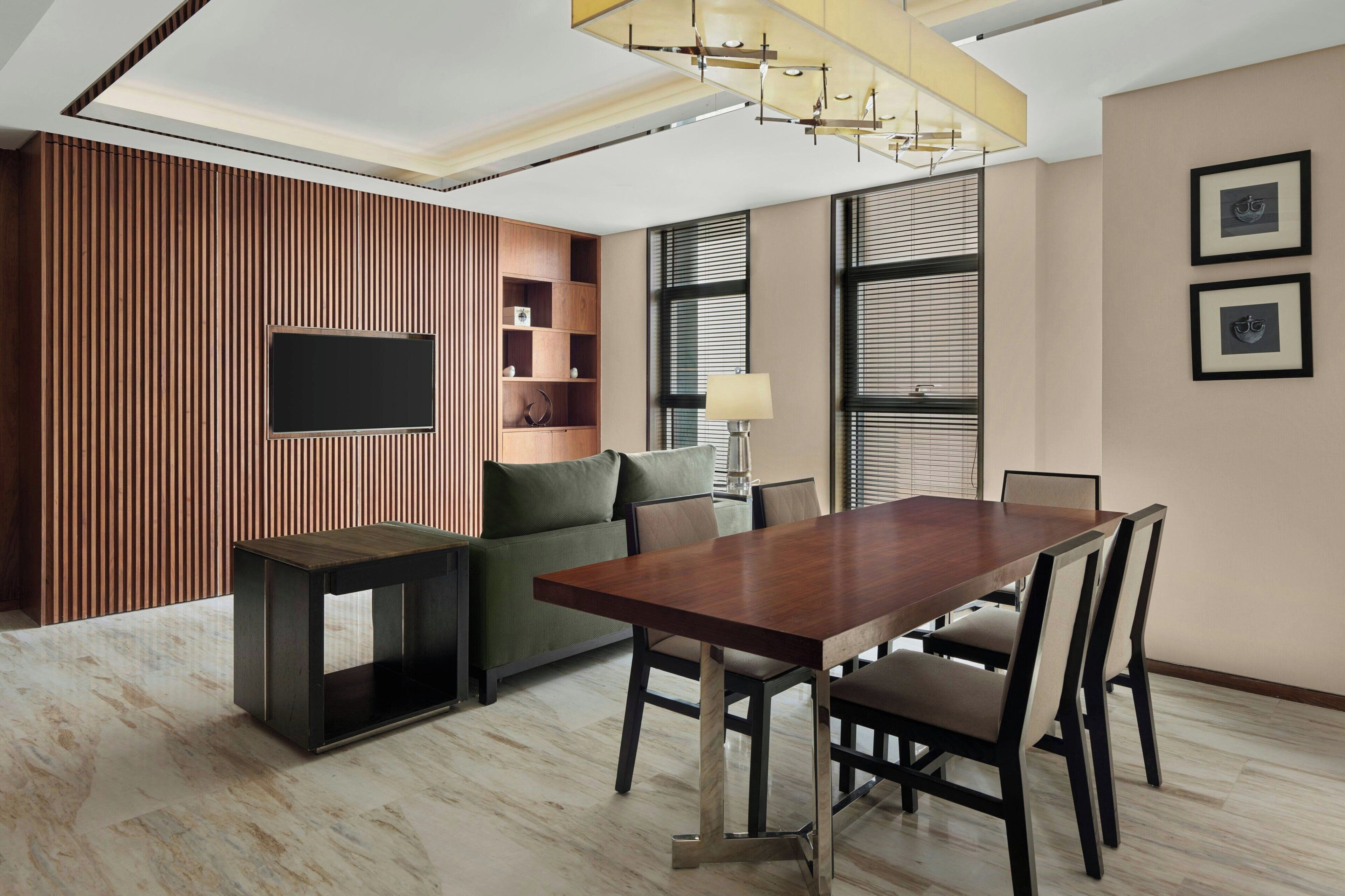 Una sala de estar moderna con una pared de acento de madera, un televisor de pantalla plana, una mesa de comedor con sillas y un sofá.