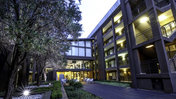 A modern building with multiple floors, large windows, and a well-lit entrance area. - The Nicol Hotel and Apartments (Germiston)