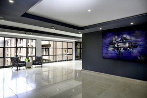 Un vestíbulo espacioso de diseño moderno, con un ventanal grande, dos sillones estampados, una mesita y un cuadro en la pared.