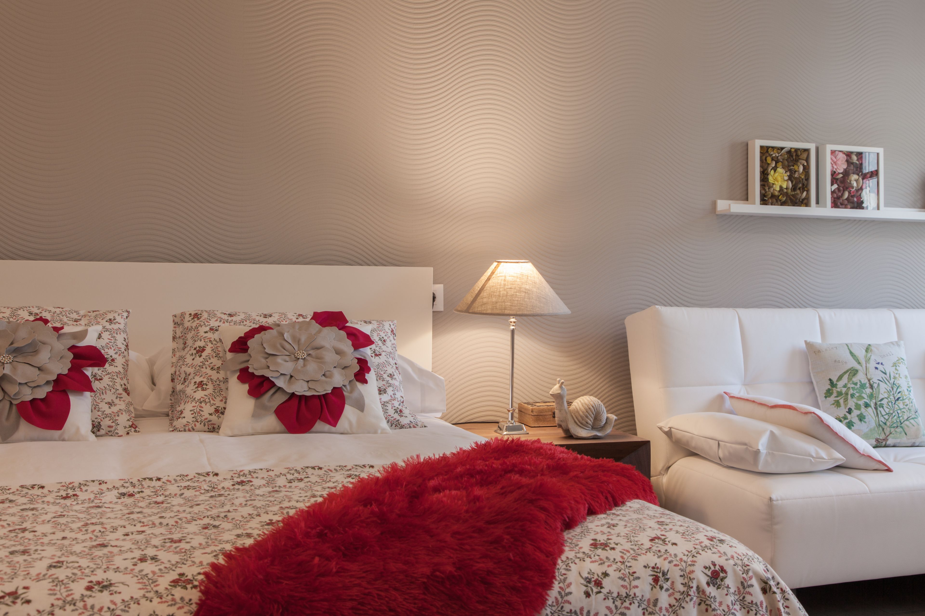 Ein ordentlich eingerichtetes Schlafzimmer mit einem Bett, einem Nachttisch, einer Lampe und einem Sofa.