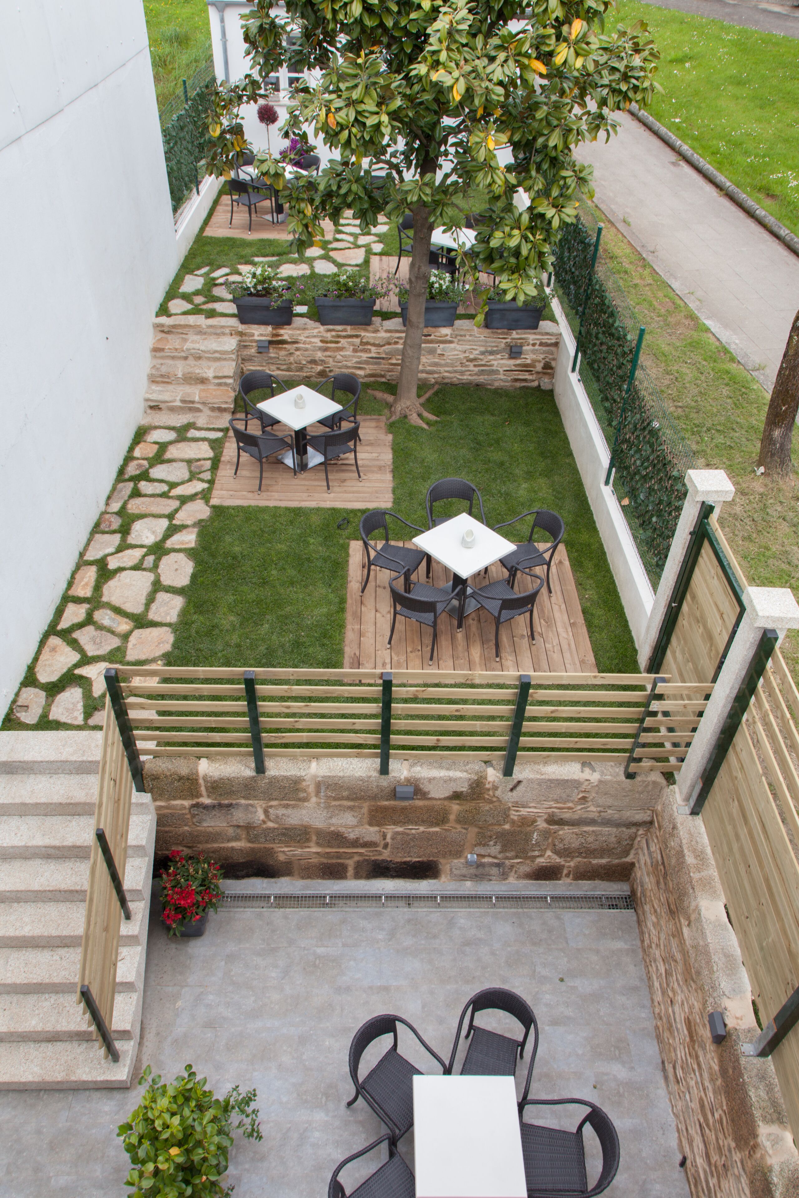 Un patio con suelo de piedra, terraza de madera y mobiliario exterior.