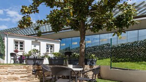 An outdoor patio with wicker furniture, a stone wall, and a tree. - Apartamentos Nova Compostela (Santiago de Compostela)