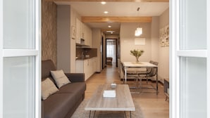 A modern living room with a brown sofa, a wooden coffee table, and a dining area with a table and chairs. - Apartamentos Nova Compostela (Santiago de Compostela)