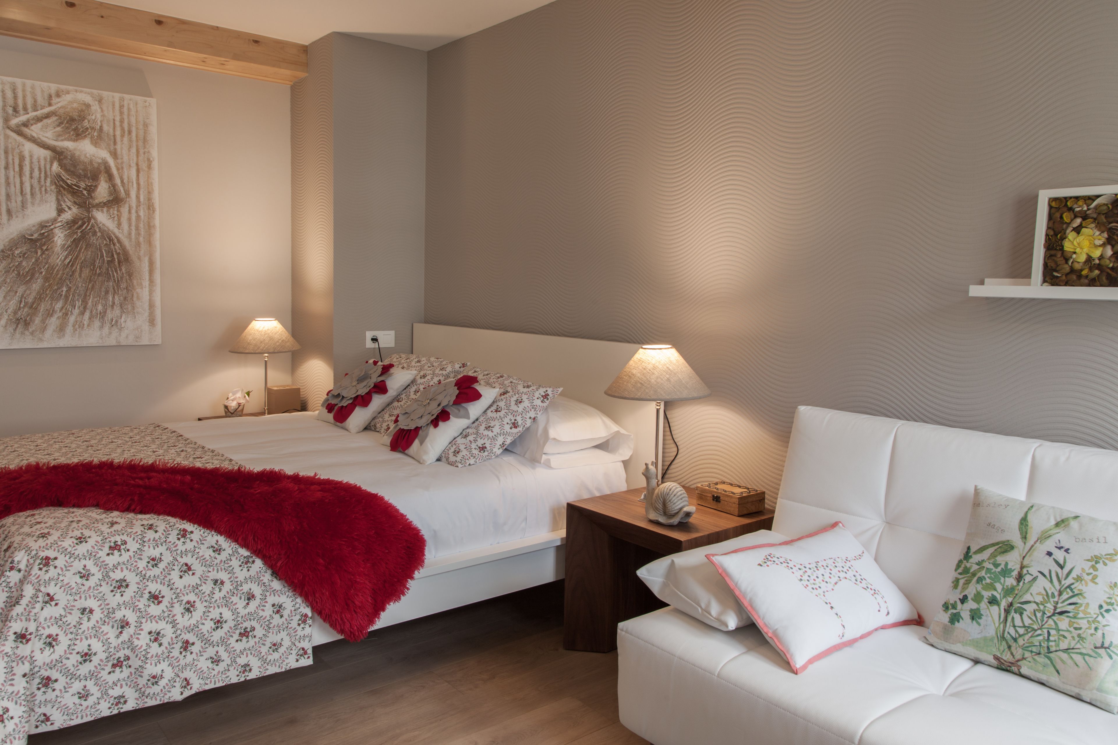 Ein Schlafzimmer mit zwei Betten, einem weißen Sofa und einem Nachttisch mit Lampen.