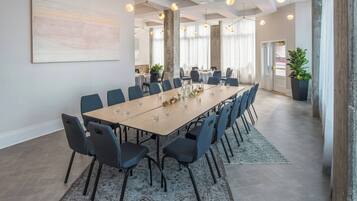 A modern conference room with a long table, chairs, and hanging lights.