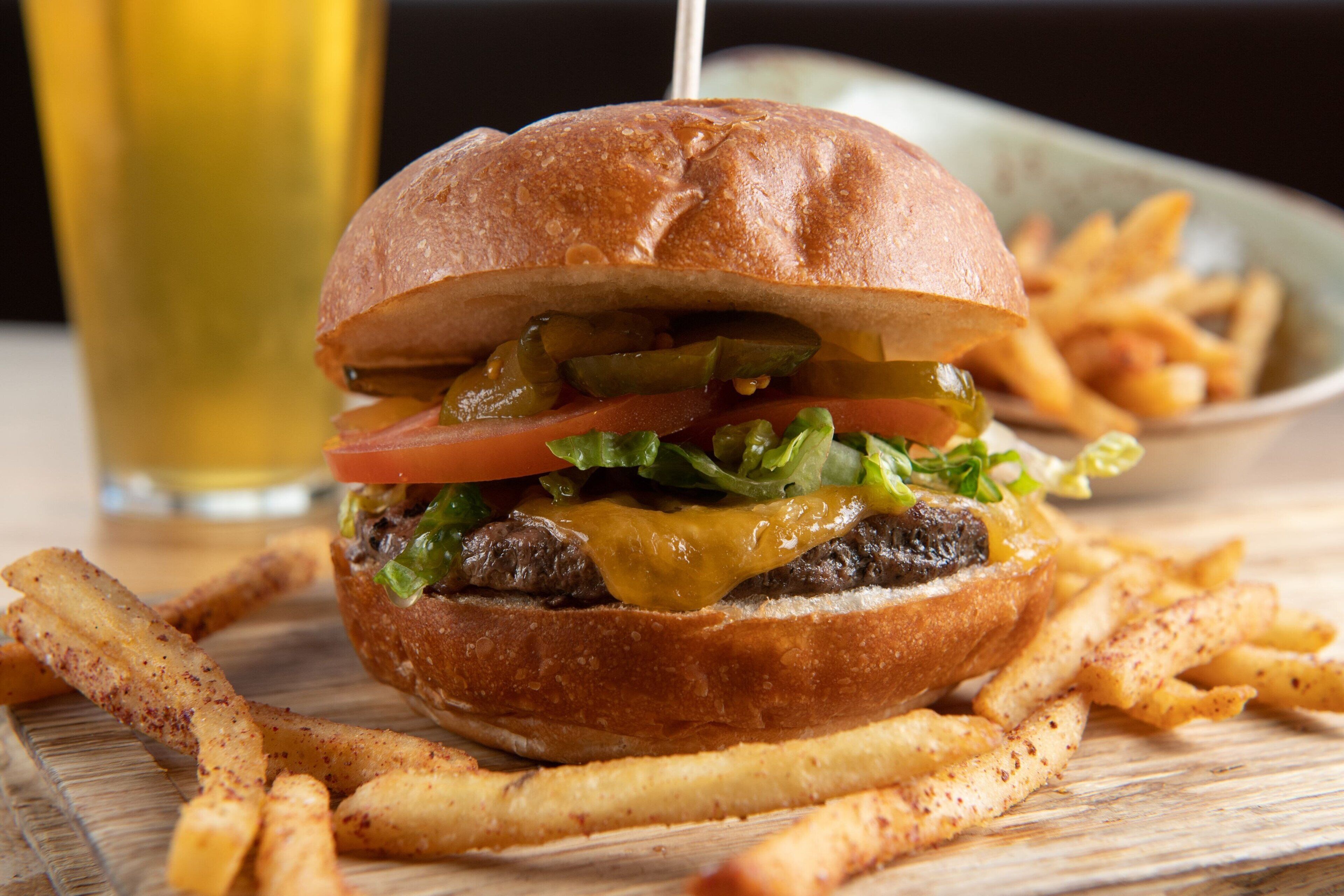 A burger with fries on a wooden board.
