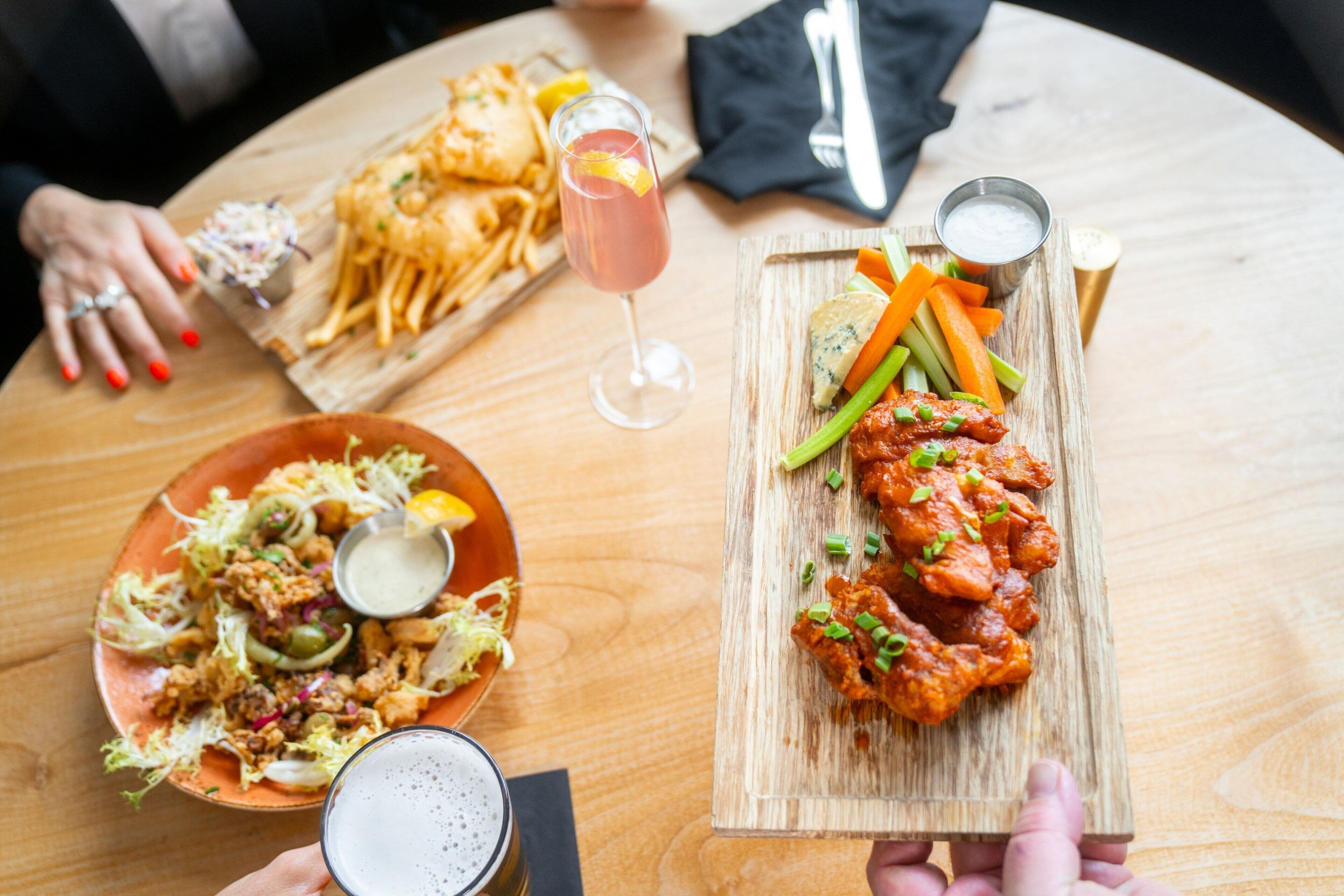 A wooden table with various dishes including fried chicken, fries, and a salad.