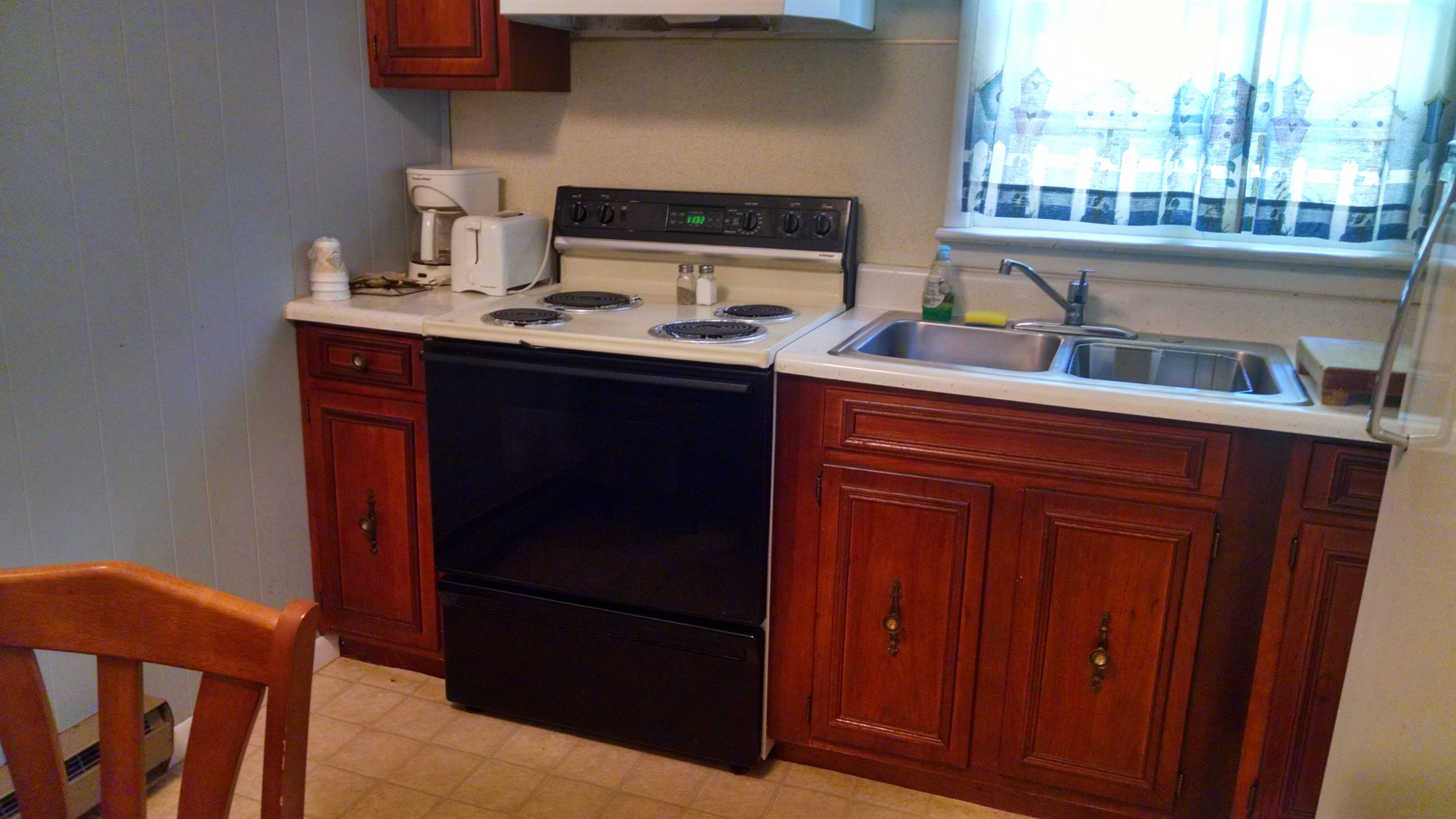 A kitchen with a stove, oven, and sink. There is a window with a view of buildings.