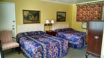 Een hotelkamer met twee bedden, een stoel, een dressoir en twee wandlampen.