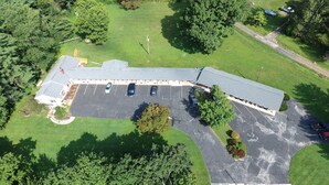 An aerial view of a building with a parking lot, surrounded by greenery.