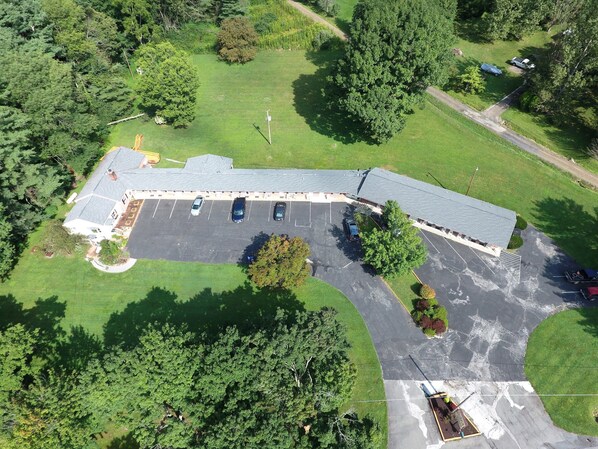 Luchtbeeld van een gebouw met een parkeerplaats, omgeven door groen.