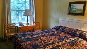 A room with a bed, a desk with a lamp, and a chair.