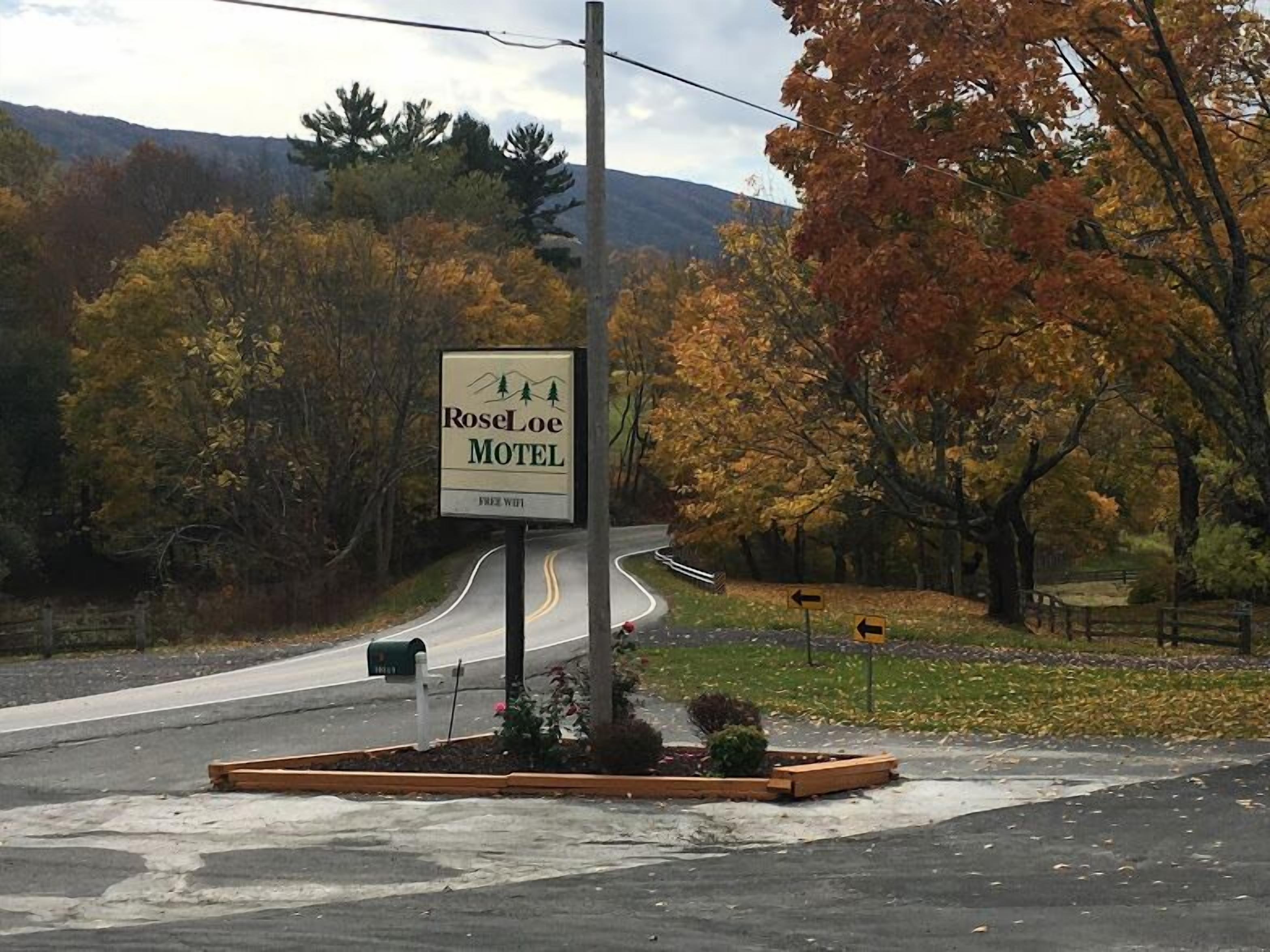 A motel sign with a mountain backdrop and autumn foliage.