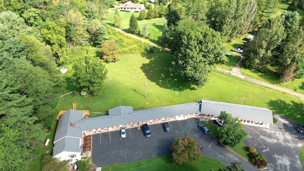 An aerial view of a building with a parking lot, surrounded by greenery.