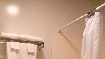 A bathroom with a toilet, a bathtub, a shower curtain, and a towel rack.
