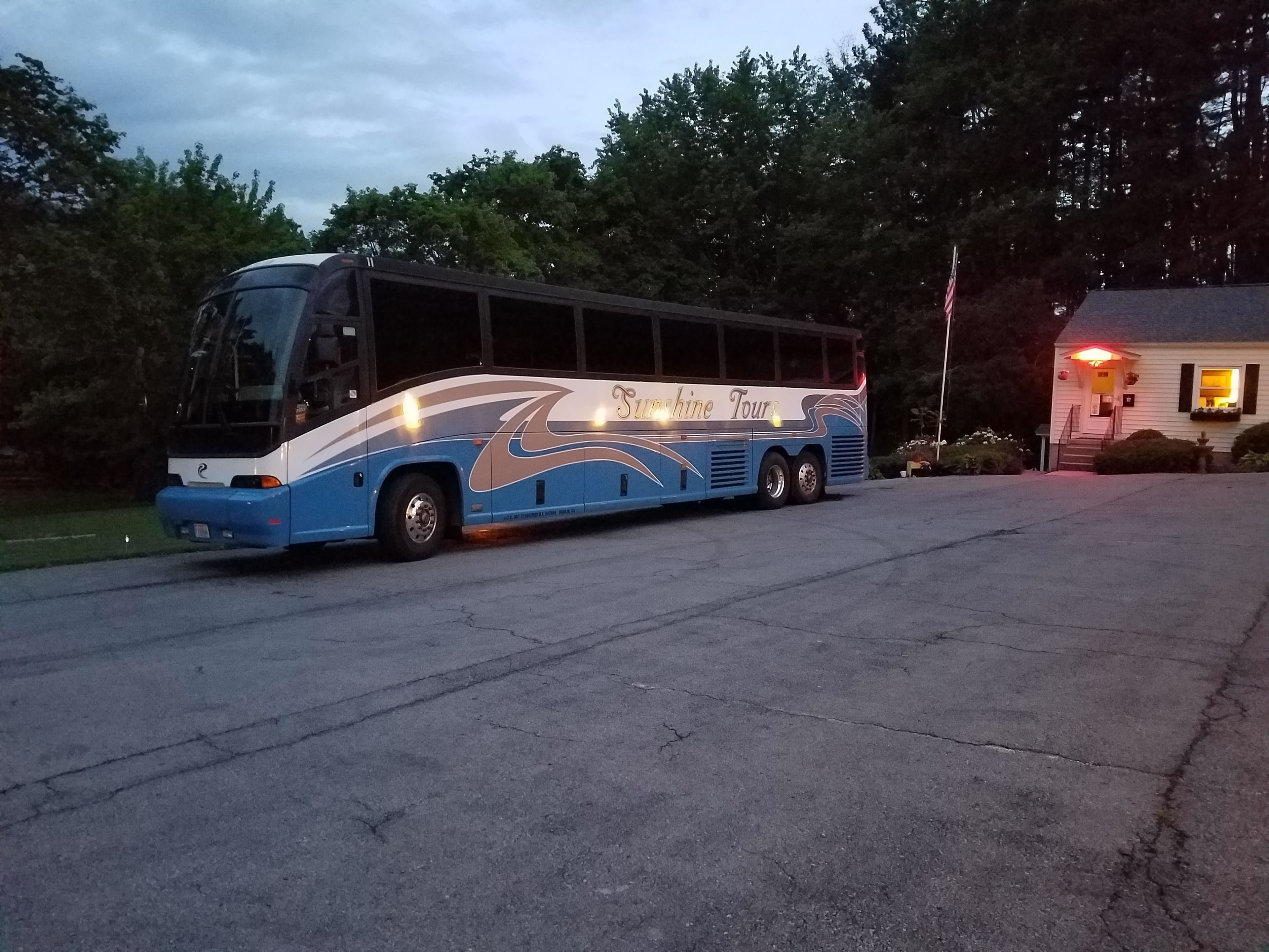 A large bus parked in front of a building with a sign that reads "Sunshine Tours."