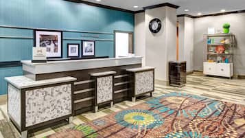Una mesa de recepción con un reloj, cuadros enmarcados y un cartel de Hilton Honors.