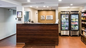 Un comptoir d’accueil avec une enseigne indiquant « Sleep Inn Suites » et deux distributeurs de boissons.