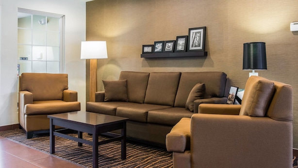 Un salon moderne comprenant un canapé, deux fauteuils, une table basse et un cadre photo fixé au mur.