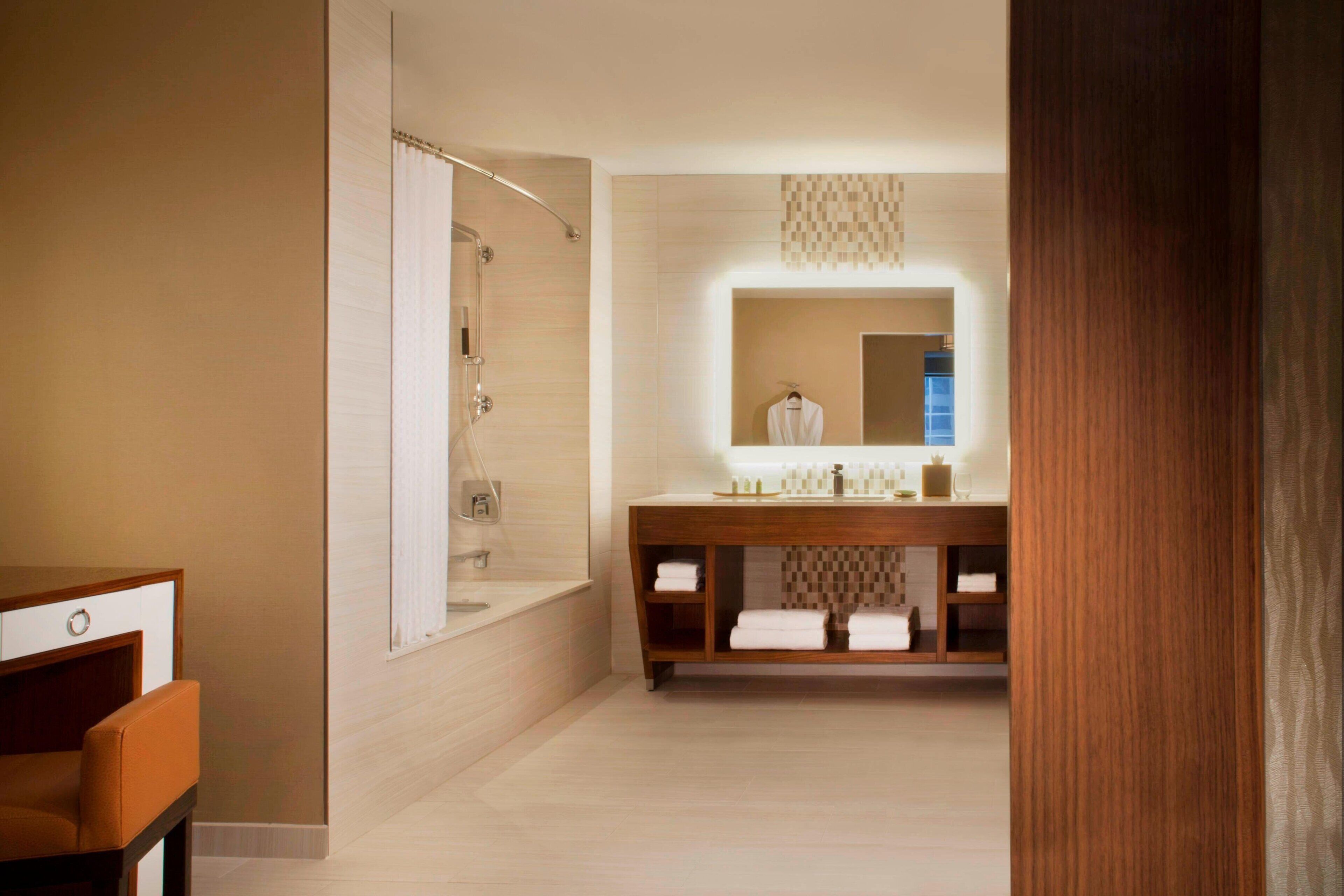 A modern bathroom with a large mirror, a vanity with shelves, and a shower area.