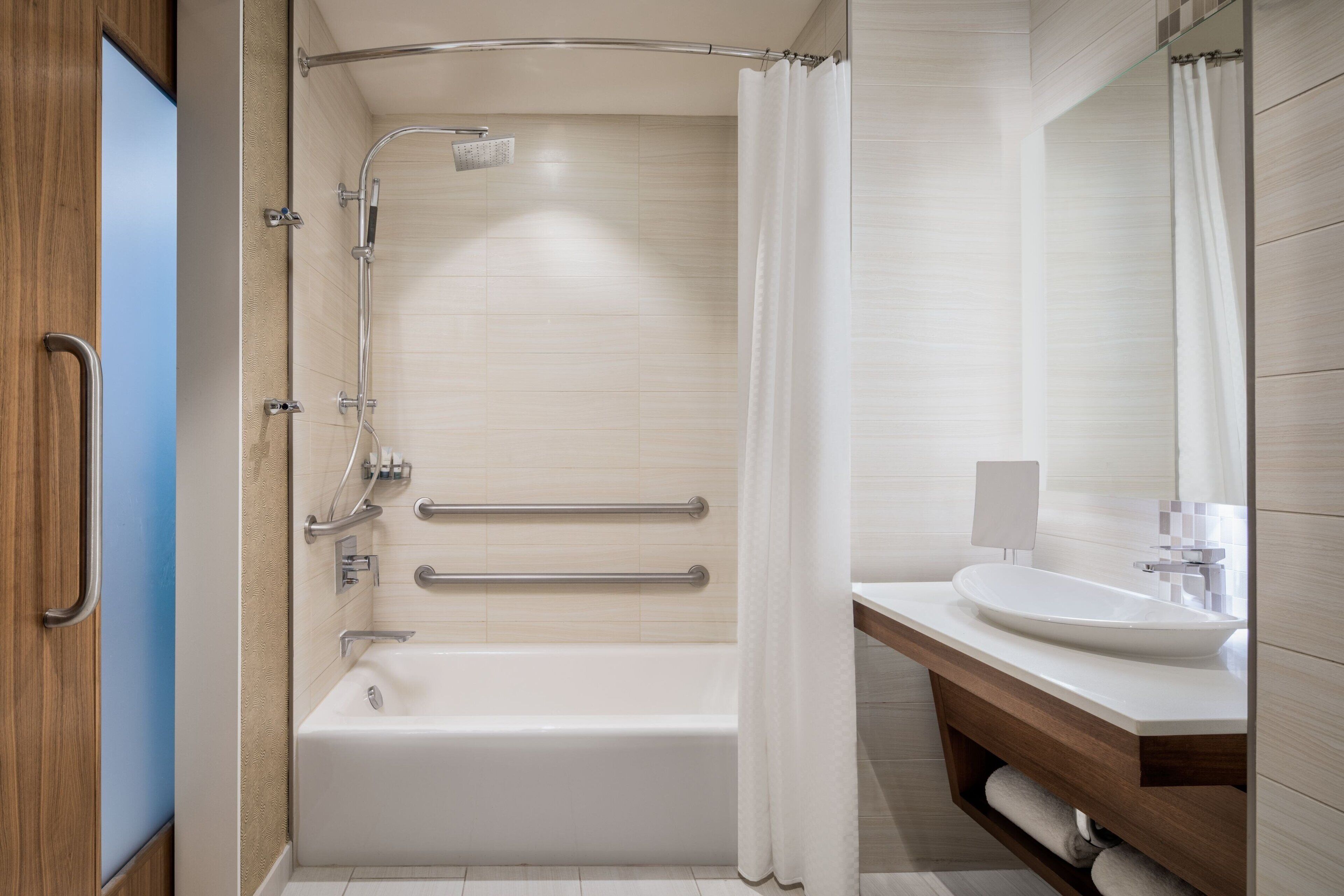 A modern bathroom with a bathtub, shower, and a vanity with a sink.