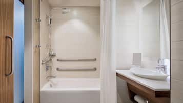 A modern bathroom with a bathtub, shower, and a vanity with a sink.
