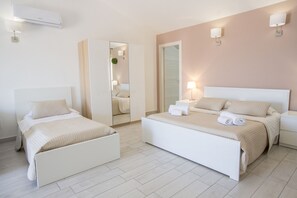 Un dormitorio moderno con dos camas, un espejo grande y un aire acondicionado de pared.
