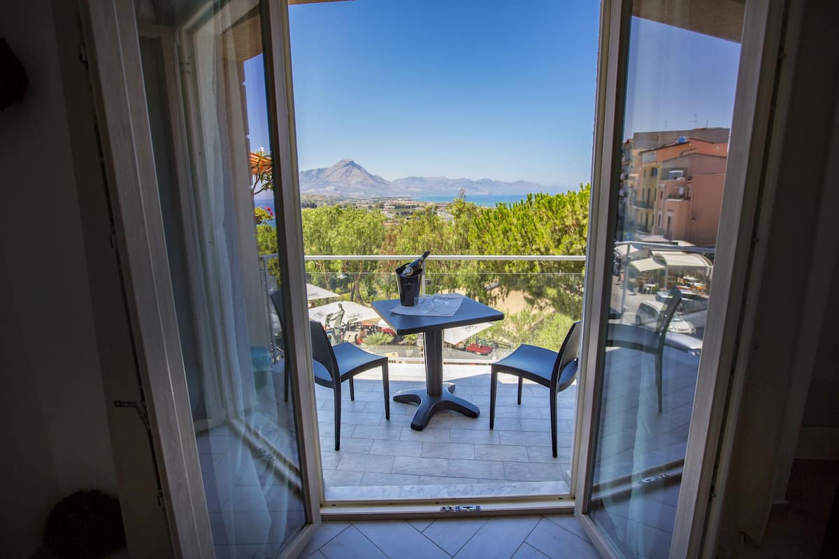 A balcony with a table and chairs, overlooking a scenic view of mountains and a body of water.