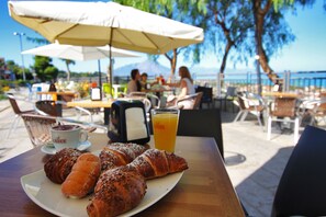 Una mesa con cruasanes, una taza de café y un vaso de zumo de naranja.