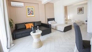 A modern living room with a black sofa, a white wicker side table, and a grey armchair. - Belvedere Rent Rooms (Campofelice di Roccella)