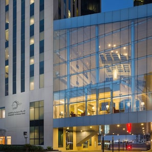 A modern hotel with a glass facade, visible interior lighting, and a staircase leading to the upper floors. - Kempinski Al Othman Hotel Al Khobar (Al Khobar)