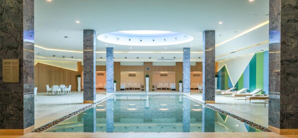 Relax by the central pool in our contemporary lobby, featuring seating areas and a reception desk.