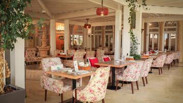 Un restaurante con sillas y mesas de estampado floral, una fuente decorativa y un ambiente cálido y acogedor.