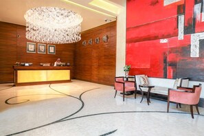 Welcome to our hotel lobby, featuring a reception desk, comfortable seating area, and elegant chandelier.