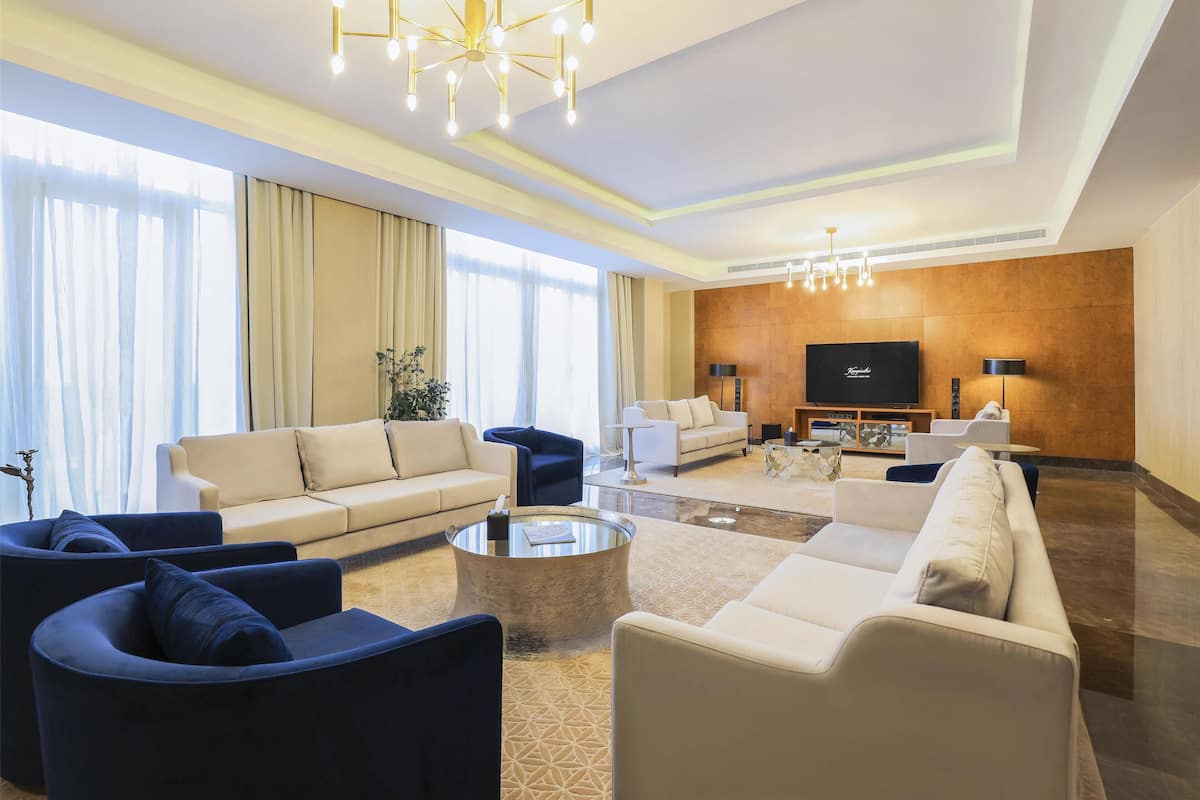 Ein modernes Wohnzimmer mit großem Fernseher, Sofas und einer Deckenleuchte.