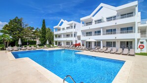 Um hotel moderno com uma piscina grande, várias varandas e espreguiçadeiras.