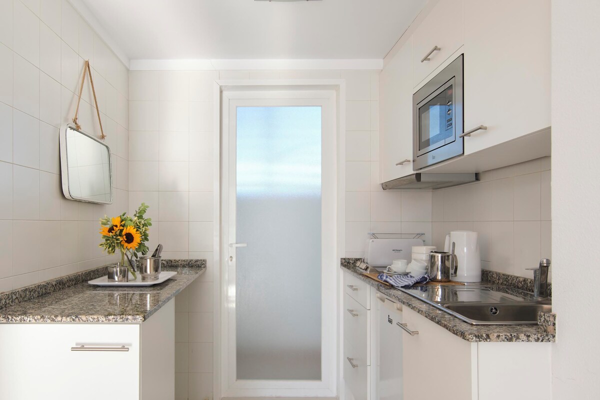 A modern kitchen with white cabinets, a granite countertop, a microwave, and a coffee maker.