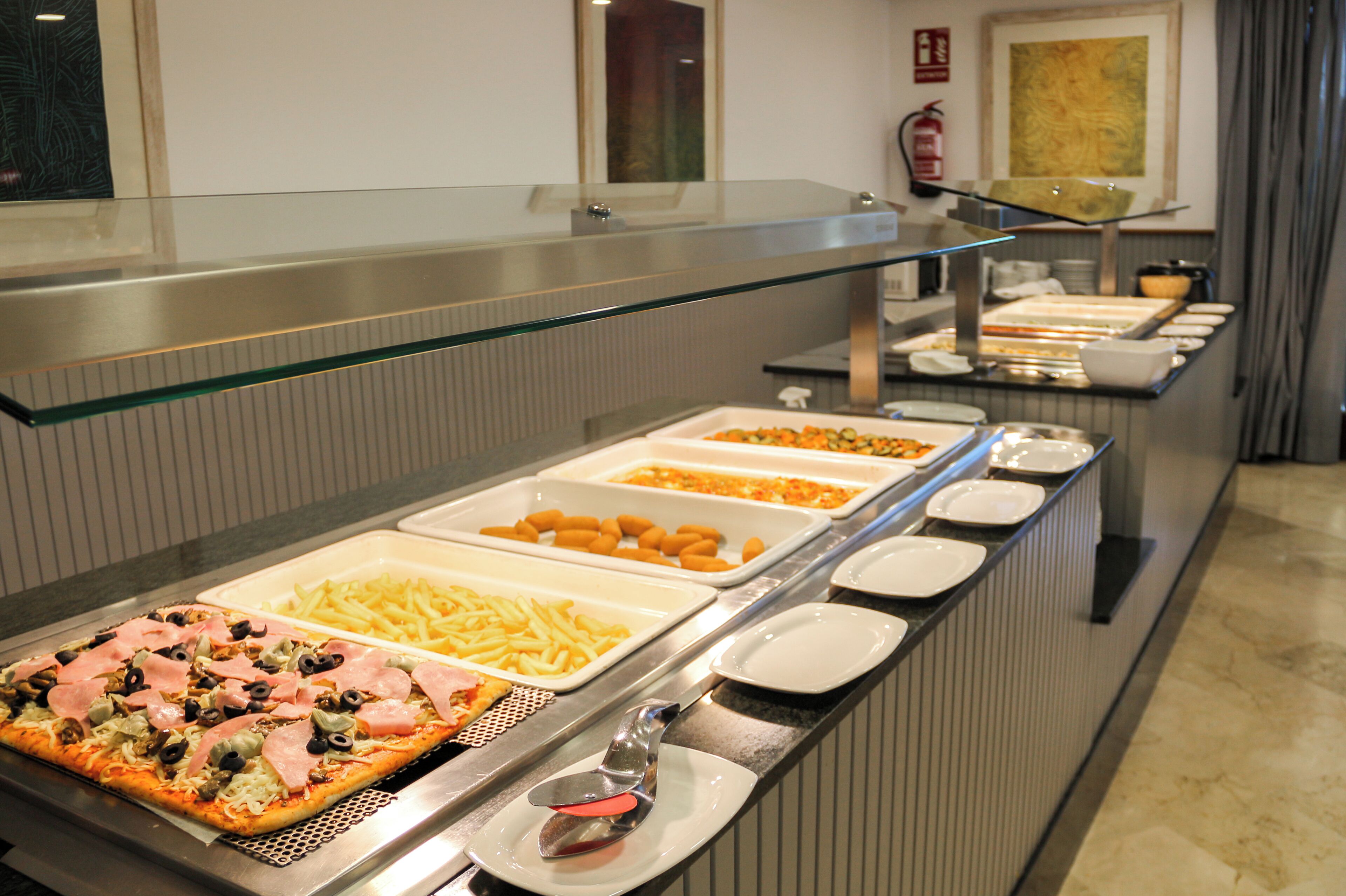 A buffet with various food options including pizza, French fries, and other dishes.
