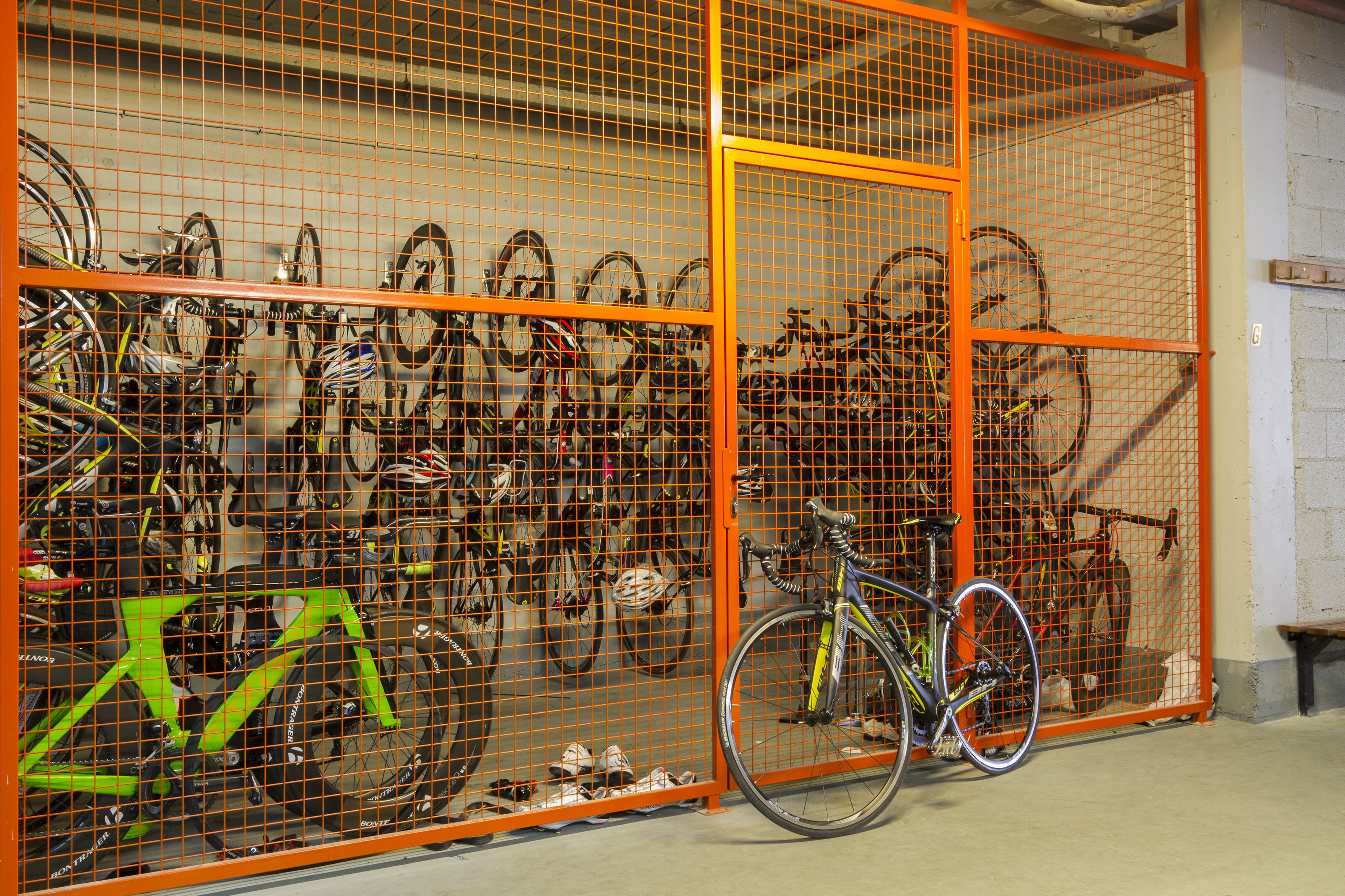 A storage area with multiple bicycles secured in an orange metal cage.
